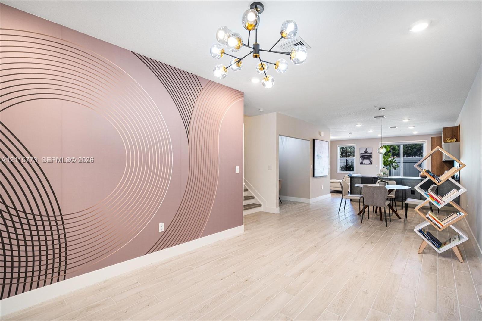Accent wall with geometric patterning, wood-finish flooring, multi-globe chandelier, and recessed lighting