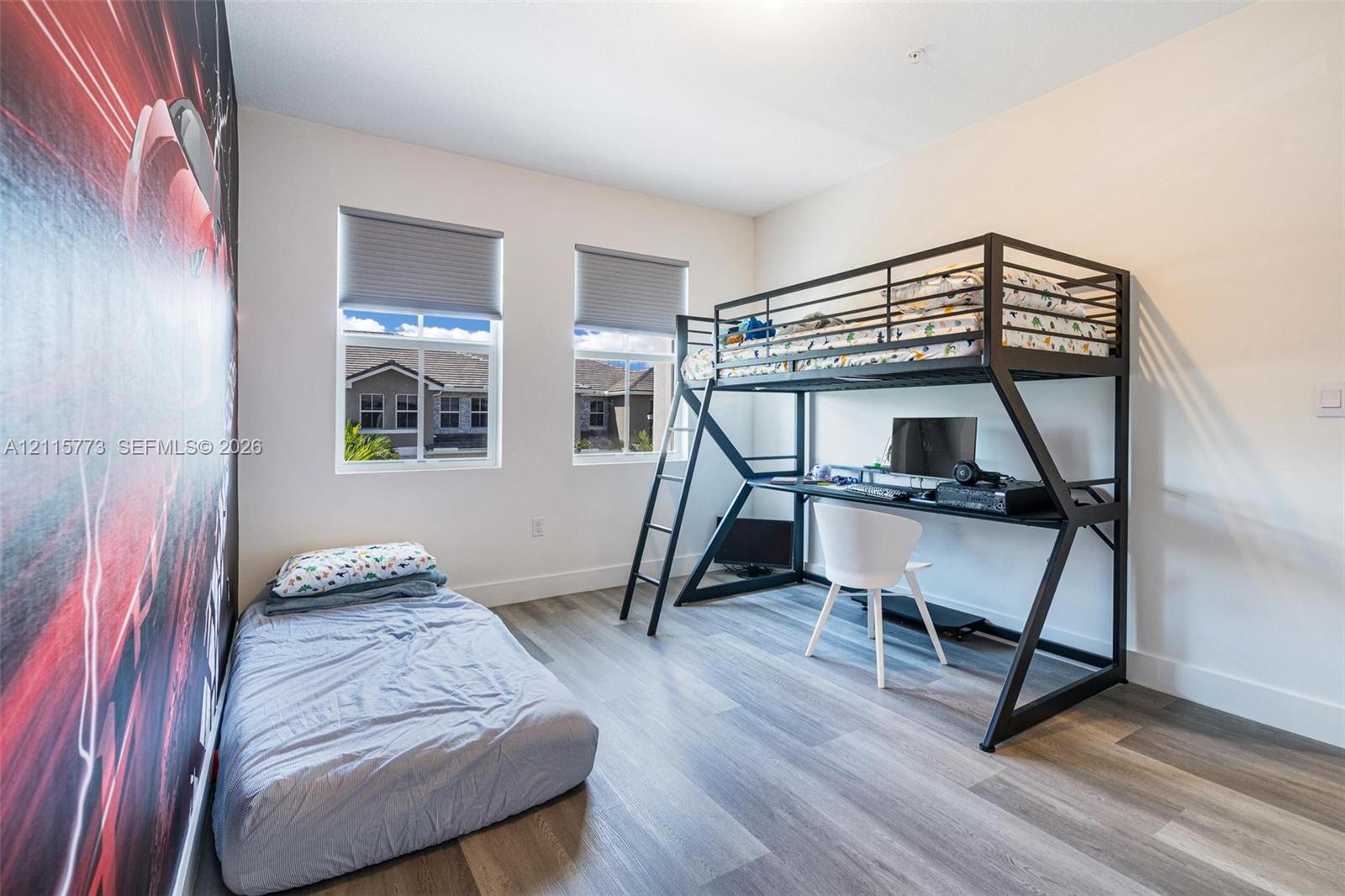 Room featuring neutral wall paint, wood-finish flooring, and two windows with installed window coverings