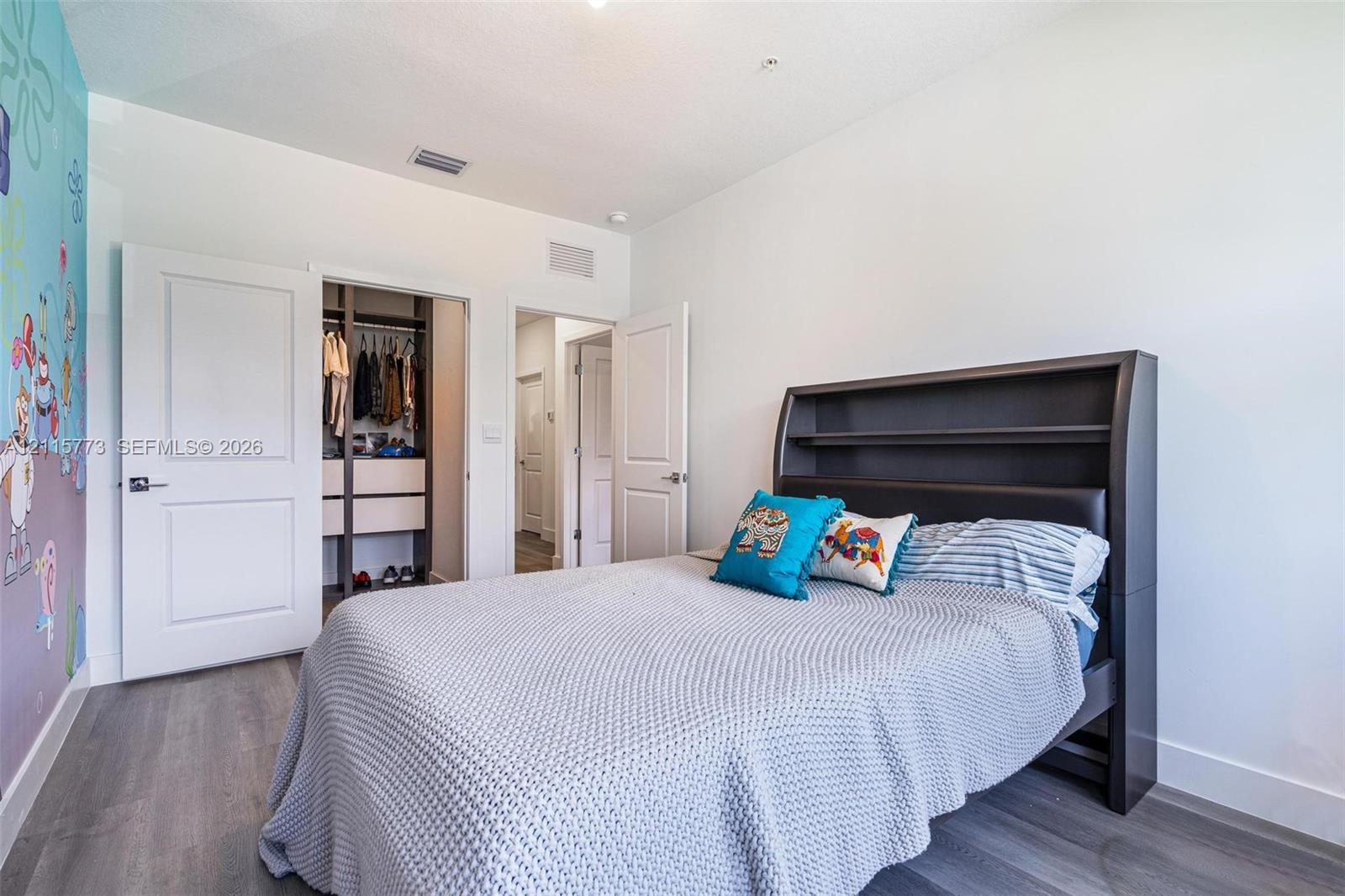 Interior space featuring wood-finish flooring, white paneled doors, and a built-in closet system with integrated shelving