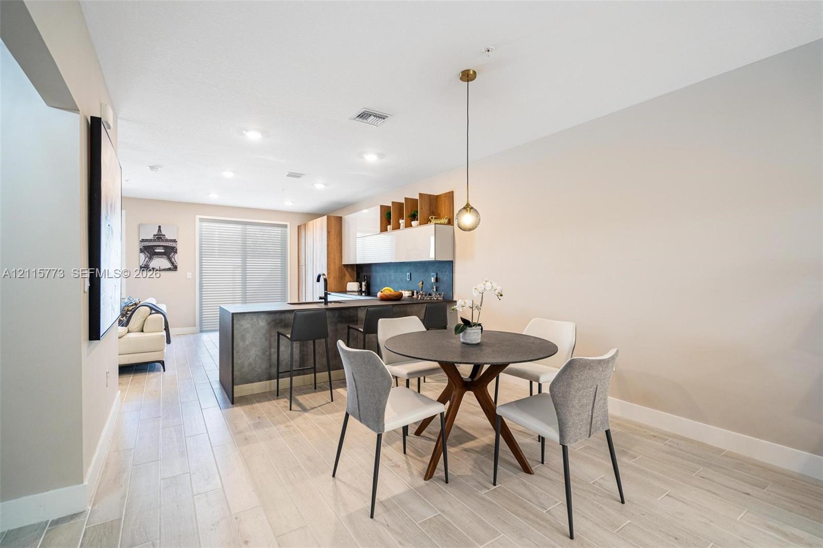 Kitchen featuring an island with a dark textured finish, light-toned flat-panel cabinetry, open shelving, tile flooring, and a modern pendant light fixture