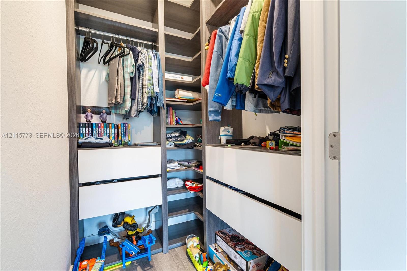 Custom built-in closet organization system featuring dark wood-finish cabinetry, white matte-finish drawers, adjustable shelving, and integrated clothing rods