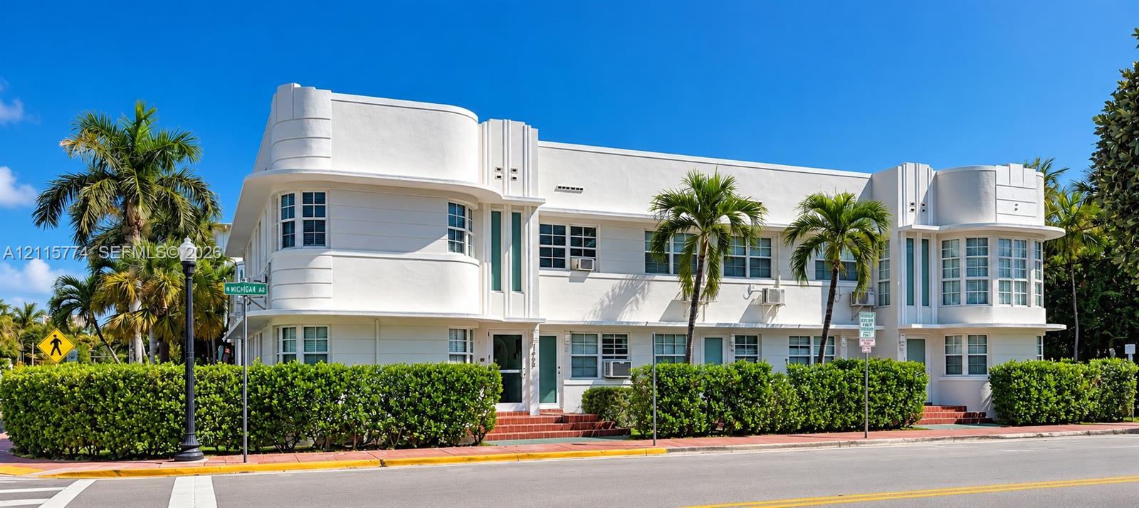 Art Deco exterior featuring rounded building corners, multi-pane casement windows, vertical decorative masonry detailing, and a smooth white stucco facade