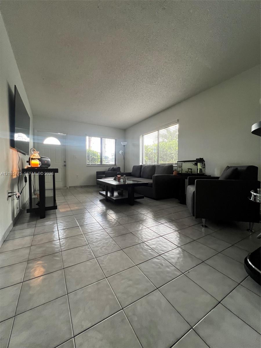 Neutral ceramic tile flooring, multiple windows providing natural light, and a dedicated entry door