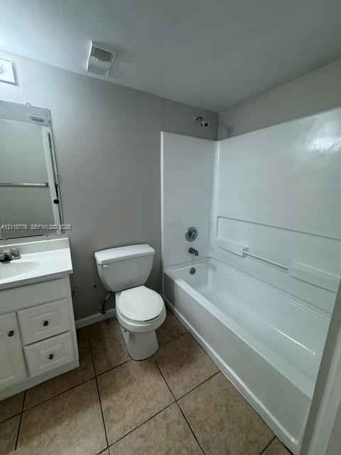 Bathroom featuring a white vanity with a composite countertop, framed wall mirror, tile flooring, and a shower-tub combination with a white surround
