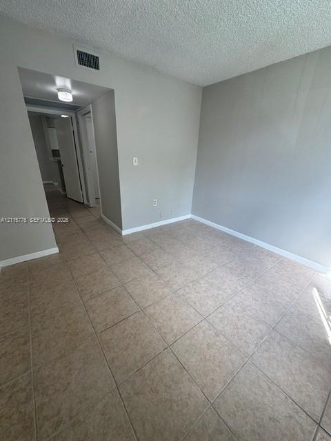 Neutral-toned interior featuring large-format ceramic floor tiling, textured ceiling finish, and recessed overhead lighting
