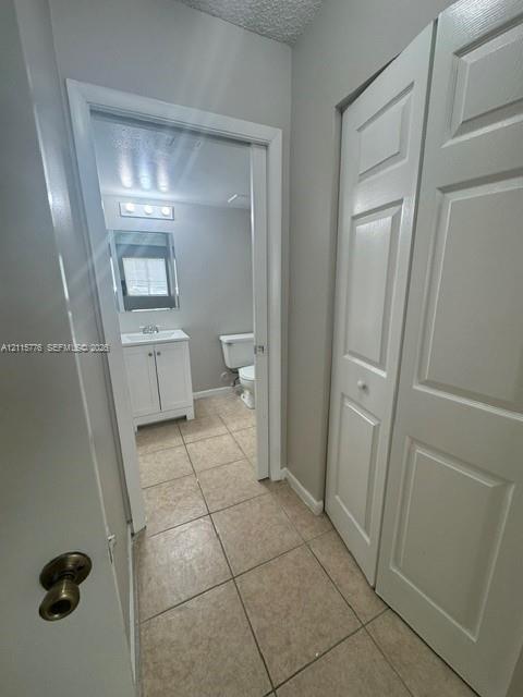Ceramic tile flooring, white shaker-style vanity cabinet, tri-light fixture, and bi-fold closet doors