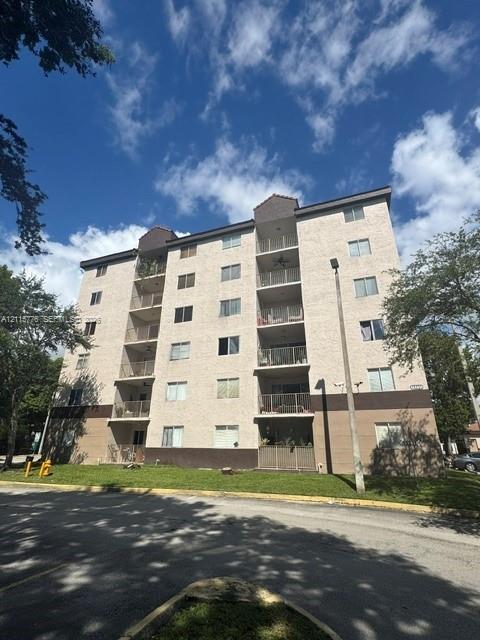 Multi-story stucco exterior featuring stacked private balconies, a flat roofline, and paved perimeter grounds Multi-story stucco exterior featuring stacked private balconies, a flat roofline, and paved perimeter grounds