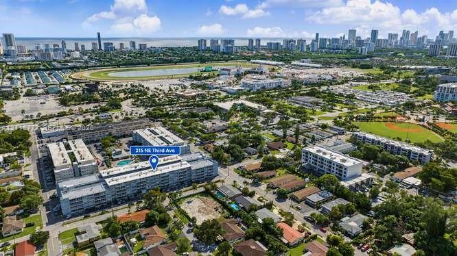 Aerial perspective of multi-story residential building featuring a swimming pool, flat roofing, and proximity to municipal park grounds