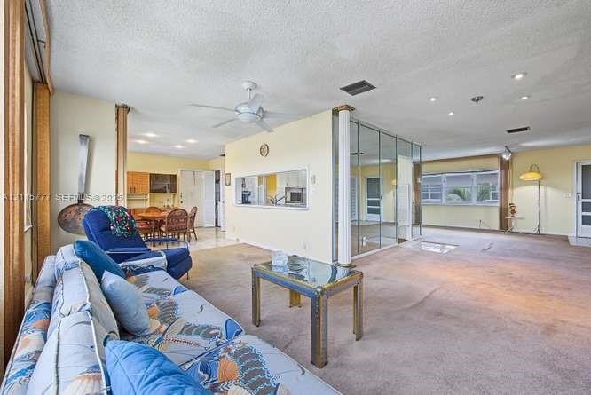 Open-concept interior featuring recessed lighting, a ceiling fan, a structural support column, and mirrored accent wall panels