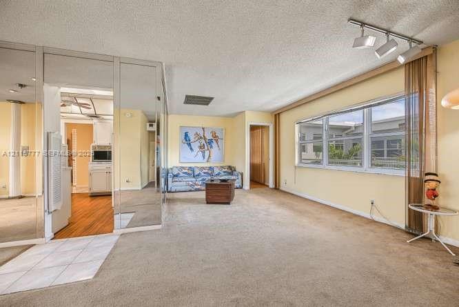 Spacious interior featuring full-wall mirrored paneling, large-format windows with track lighting, and a combination of carpet and tile flooring