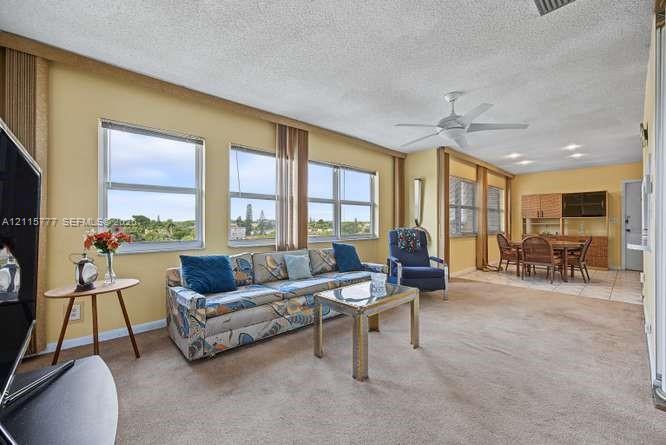 Living area featuring expansive multi-pane windows, ceiling-mounted paddle fan, recessed lighting, and built-in cabinetry