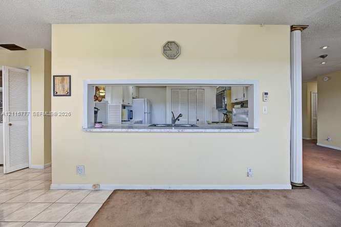 Pass-through service window featuring a stone-look countertop, integrated double-basin sink with a gooseneck faucet, and a decorative column accent