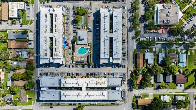 Aerial perspective of a multi-building residential complex featuring surface parking lots and a centrally located swimming pool