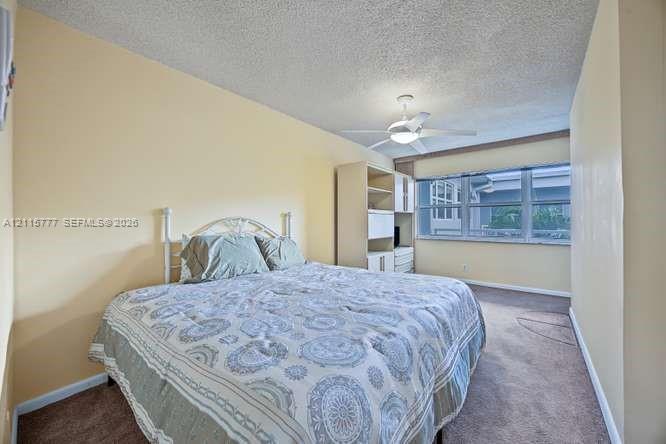 Bedroom featuring large windows, neutral wall tones, carpeted flooring, a ceiling fan with integrated lighting, and built-in shelving