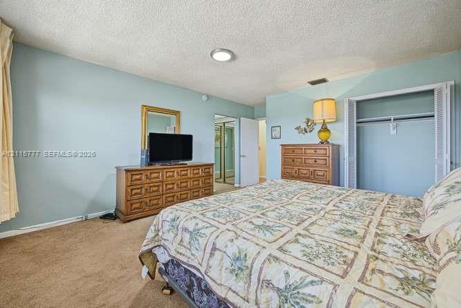 Neutral-toned carpet flooring, textured ceiling, and a built-in closet with bi-fold doors