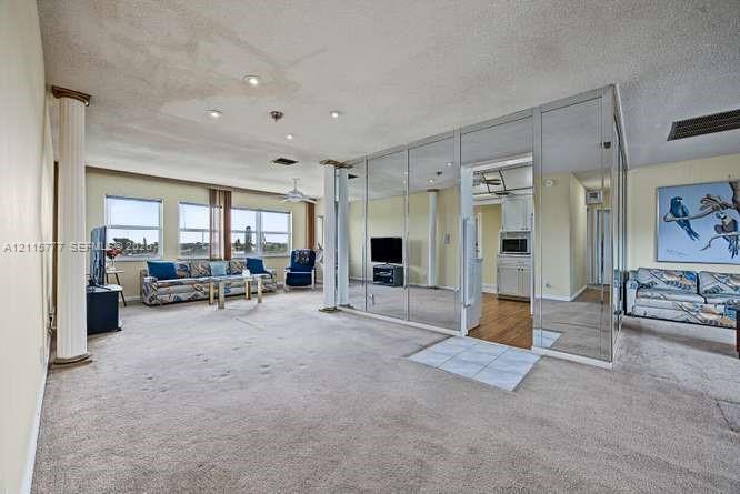 Spacious interior featuring mirrored floor-to-ceiling wall panels, decorative support columns, and multiple windows