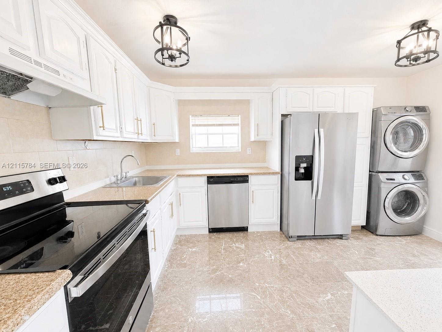 Kitchen featuring white cabinetry with brushed-gold hardware, stainless steel appliances, stone-finish countertops, tile flooring, and dual lantern-style pendant lighting