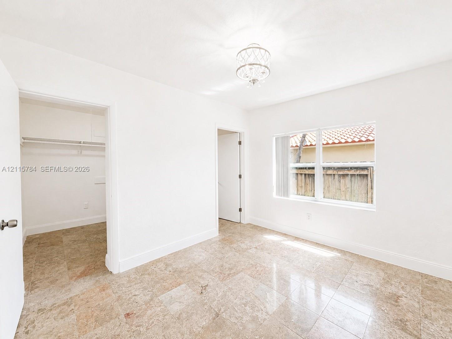 Polished stone flooring, recessed overhead lighting, and white walls featuring a multi-pane window with a neutral finish