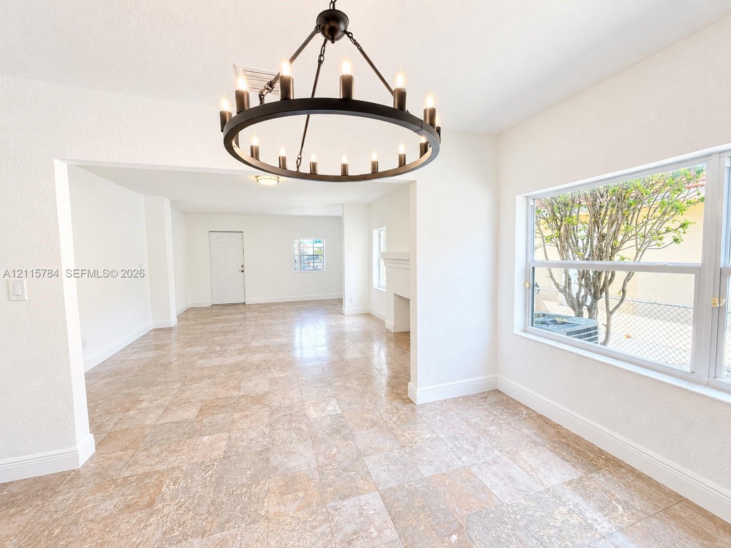 Interior space featuring large-format tile flooring, a circular multi-light chandelier, and a masonry fireplace mantel