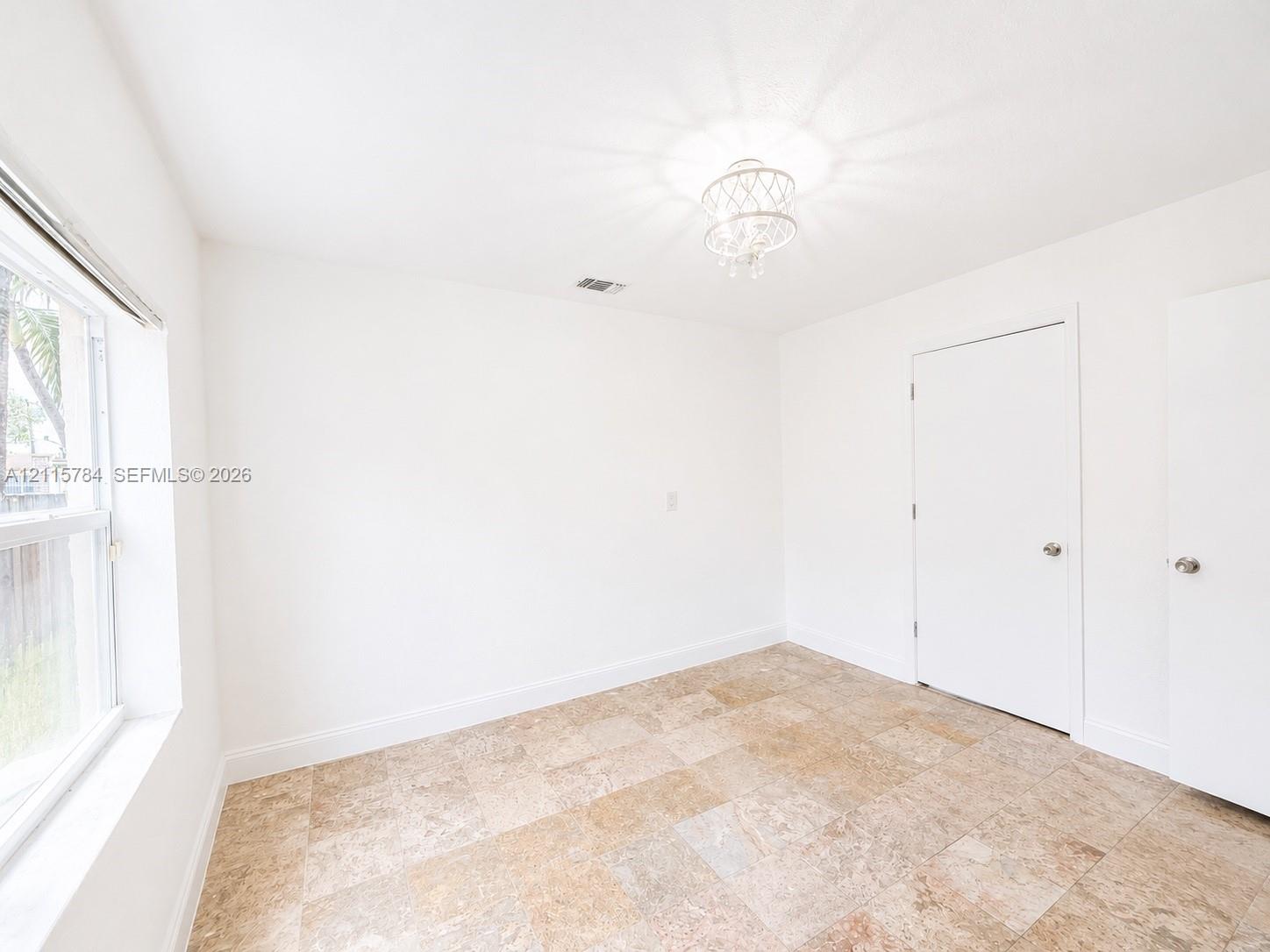 Neutral-toned stone-finish tile flooring, decorative semi-flush mount lighting, and multi-pane window with white frame