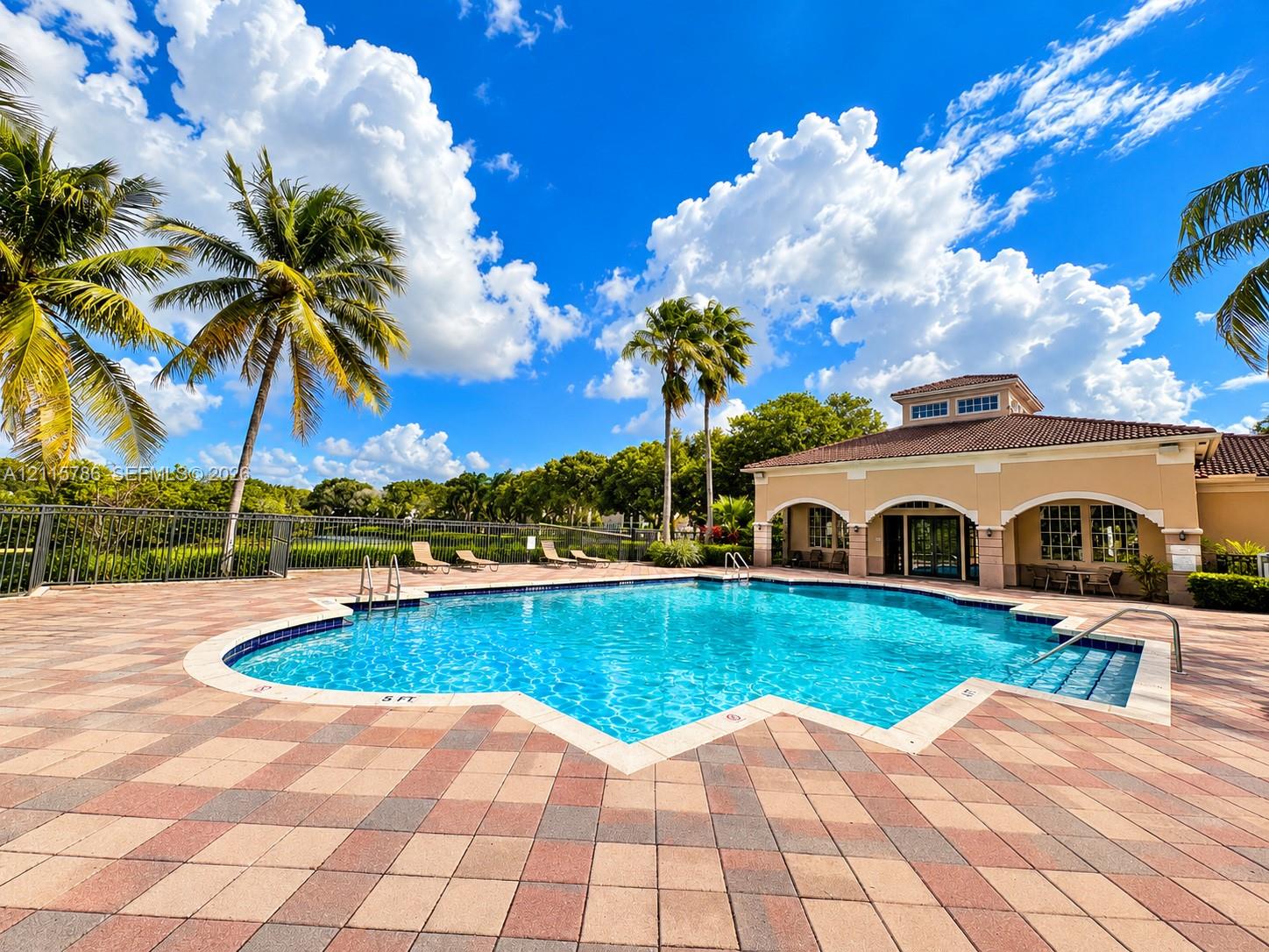 Swimming pool featuring a stone paver deck, integrated step entry, metal handrails, and architectural clubhouse building