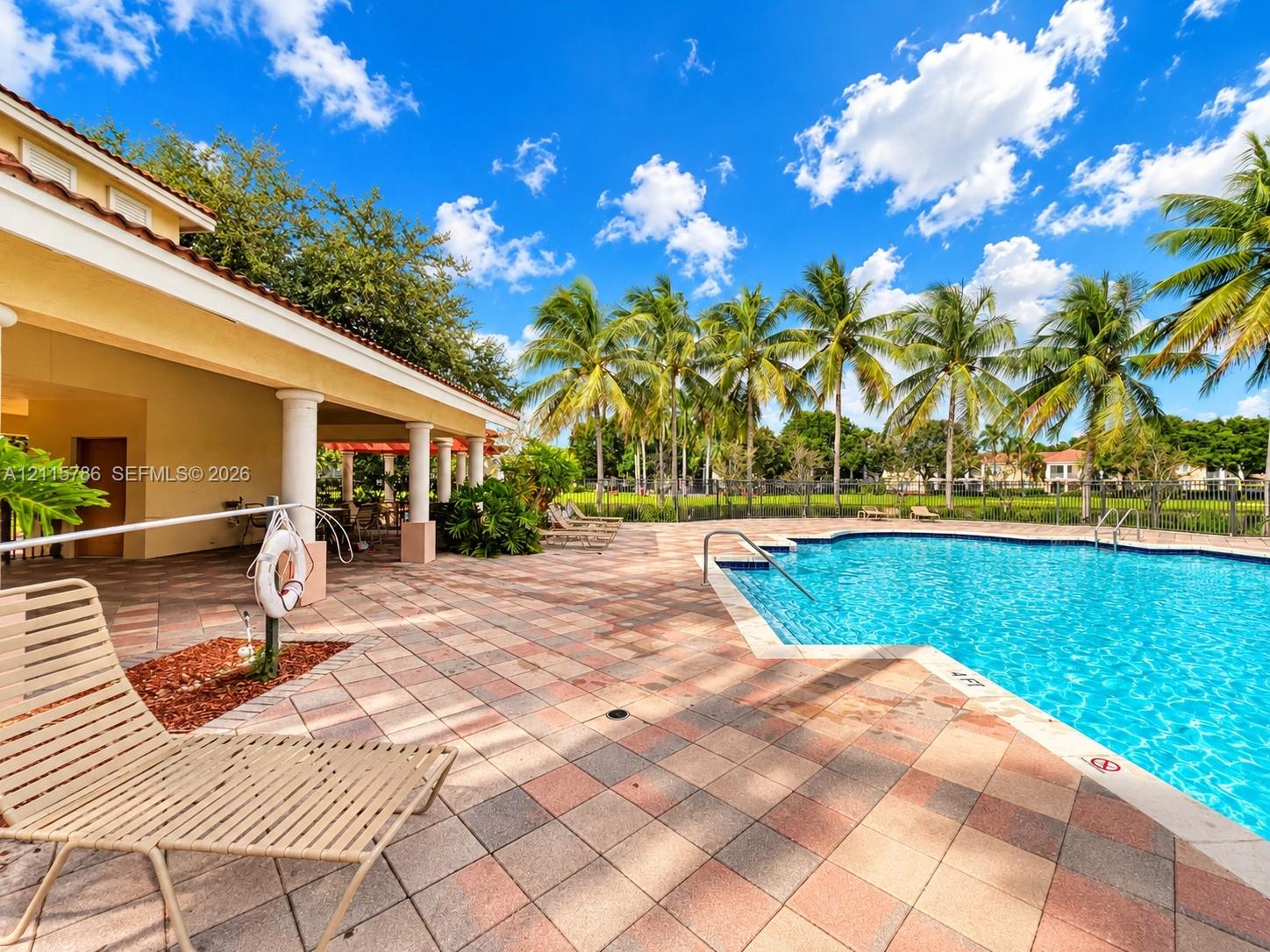 Swimming pool with a tile deck and covered patio featuring structural columns