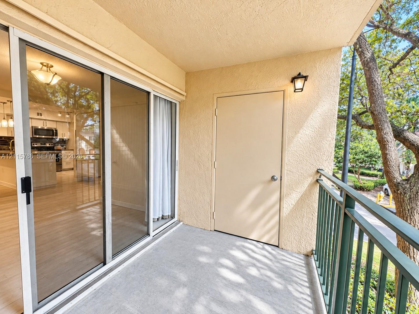 Covered balcony featuring concrete flooring, sliding glass door entry, metal railing, and an exterior storage closet