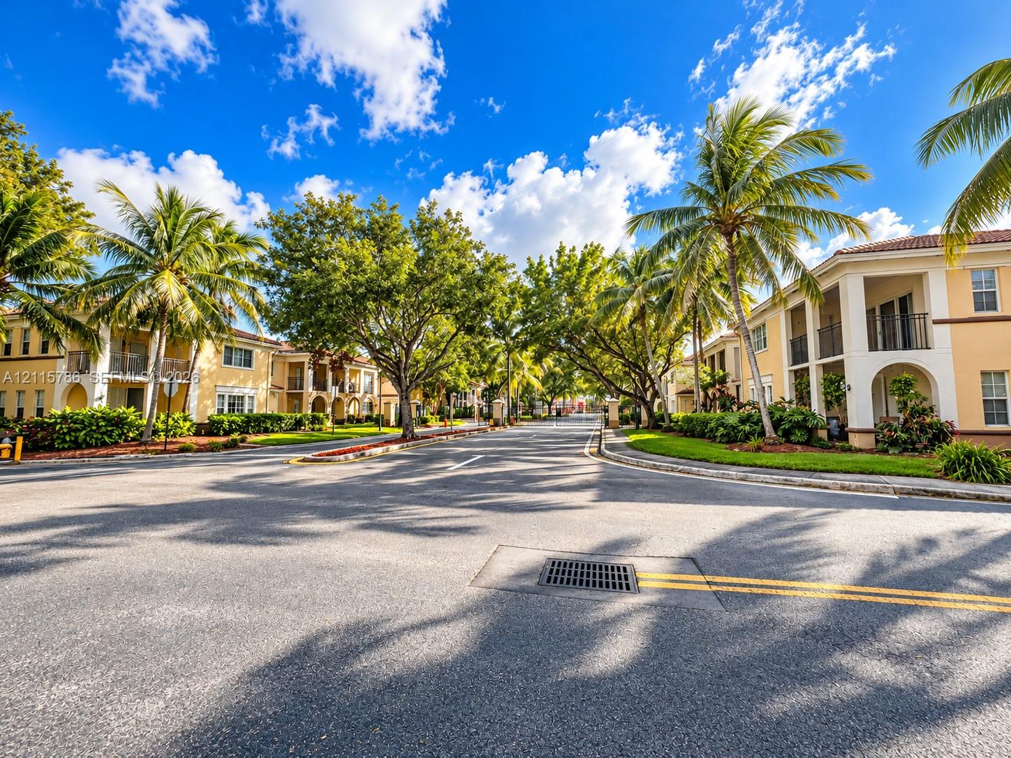 Multi-story residential buildings featuring stucco facades, arched entryways, private balconies, and extensive mature landscaping