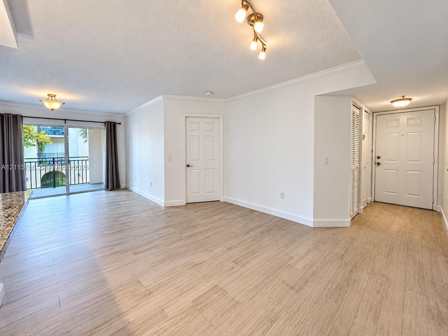Wood-finish flooring, sliding glass patio door, multi-light flush-mount ceiling fixtures, crown molding, and six-panel interior doors