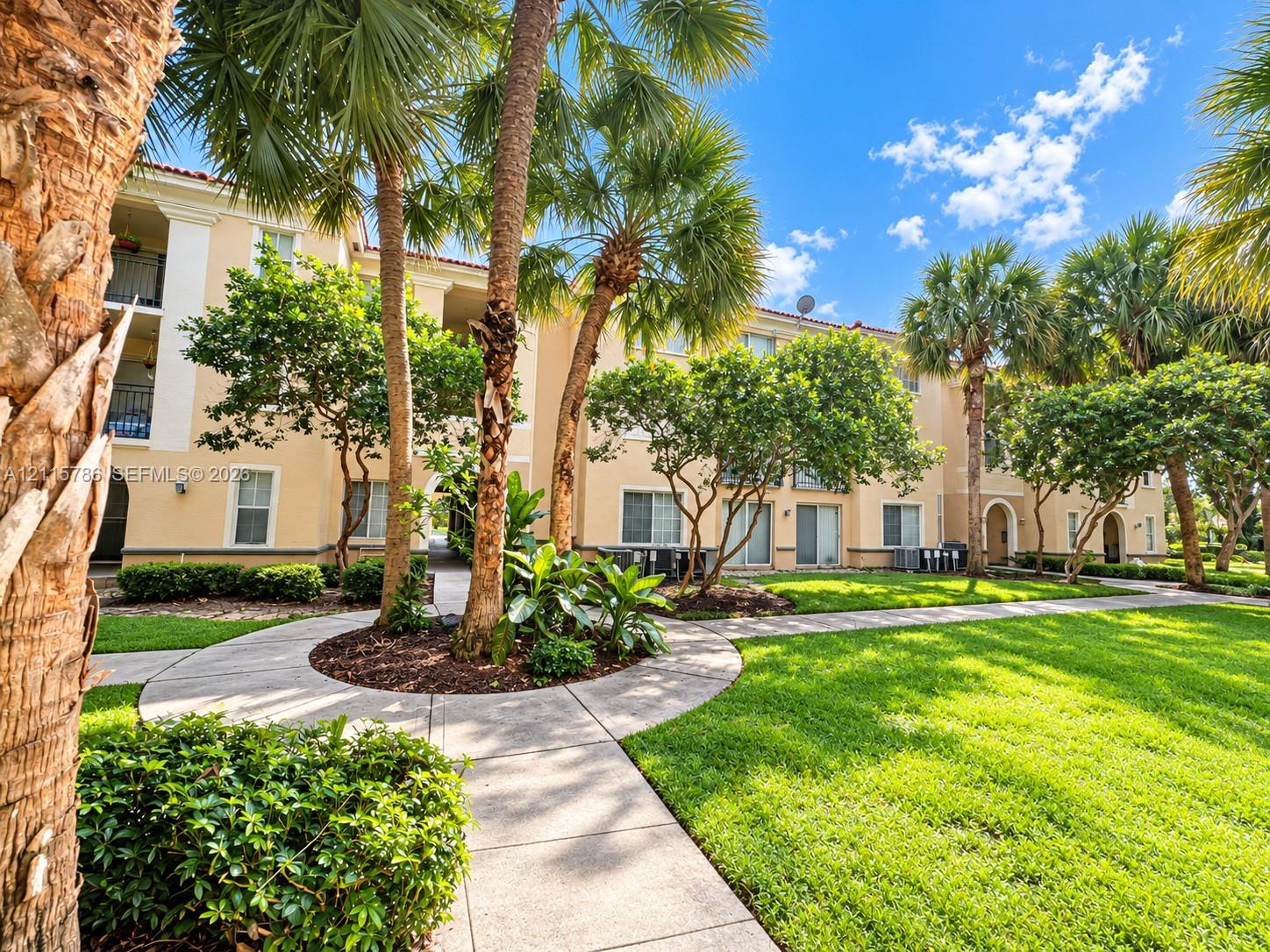 Stucco exterior featuring arched entryways and multi-level balconies, complemented by mature palm trees, professional landscaping, and concrete pathways