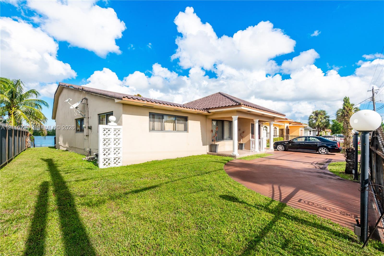 Single-story exterior featuring a tile roof, stucco siding, a covered entryway with columns, and a paved driveway