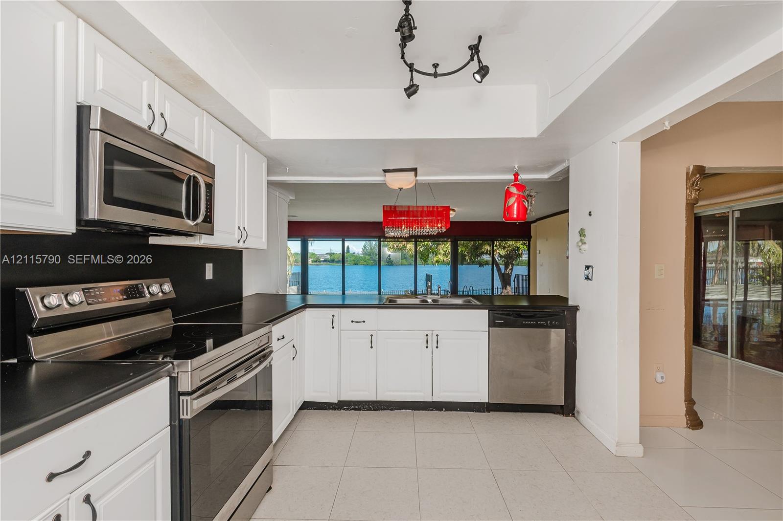 Kitchen featuring white cabinetry, stainless steel appliances, solid-surface countertops, tile flooring, and track lighting