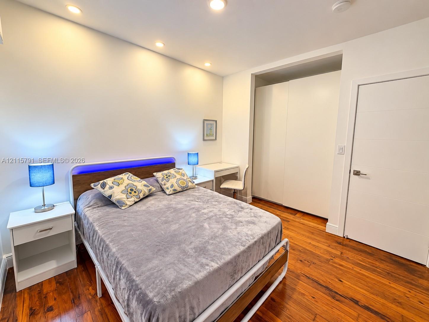 Wood-finish flooring, recessed ceiling lighting, and built-in floor-to-ceiling cabinetry with white panel doors