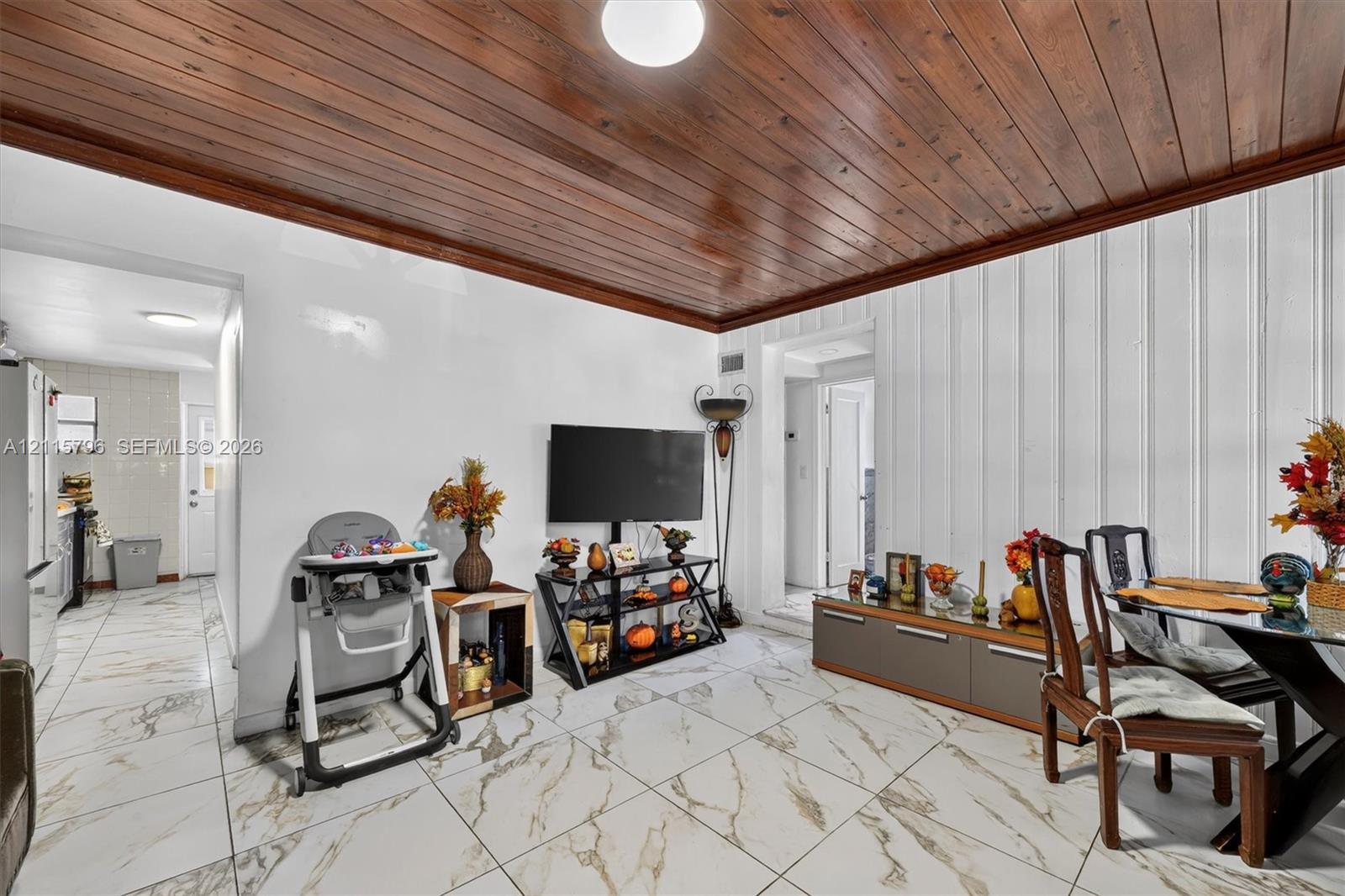 Vaulted wood-plank ceiling featuring natural finish, floor-to-ceiling vertical paneled walls, and large-format porcelain tile flooring with gold-toned veining