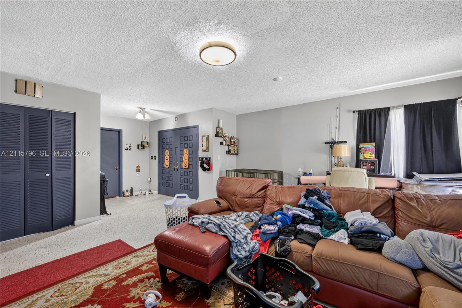 Interior space featuring textured ceilings, dual-panel interior doors, light-toned wall surfaces, and flush-mount ceiling light fixtures