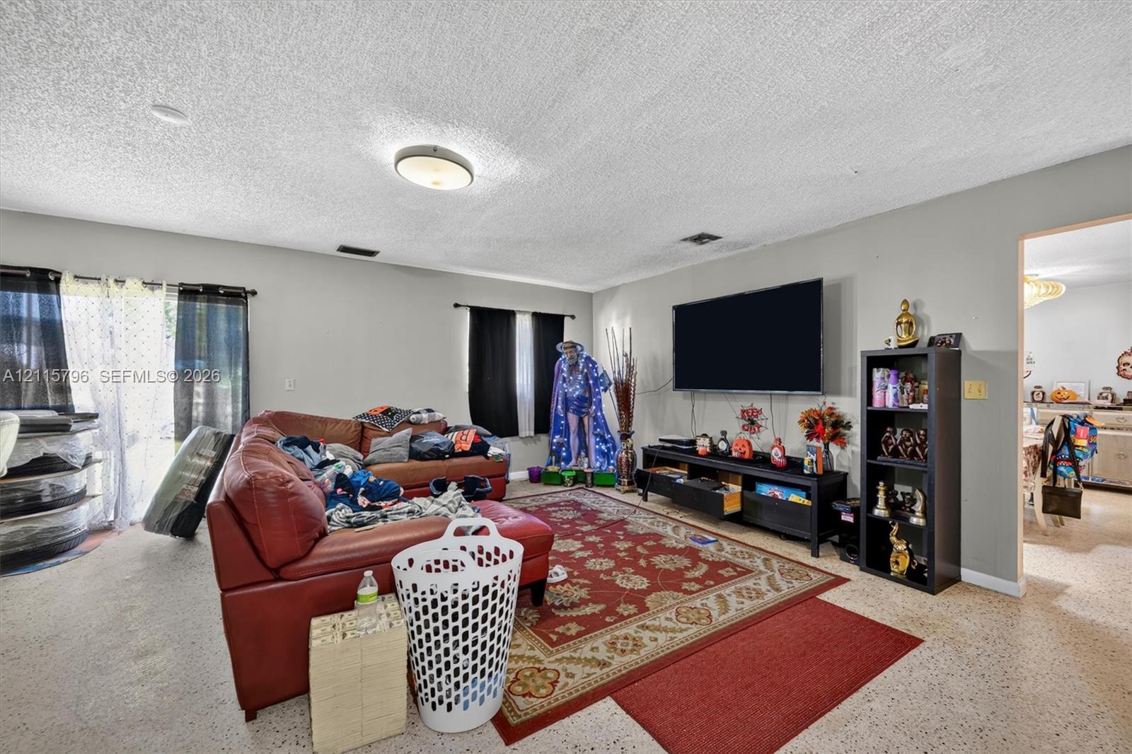 Living area featuring neutral-toned walls, terrazzo flooring, and a flush-mount ceiling light fixture