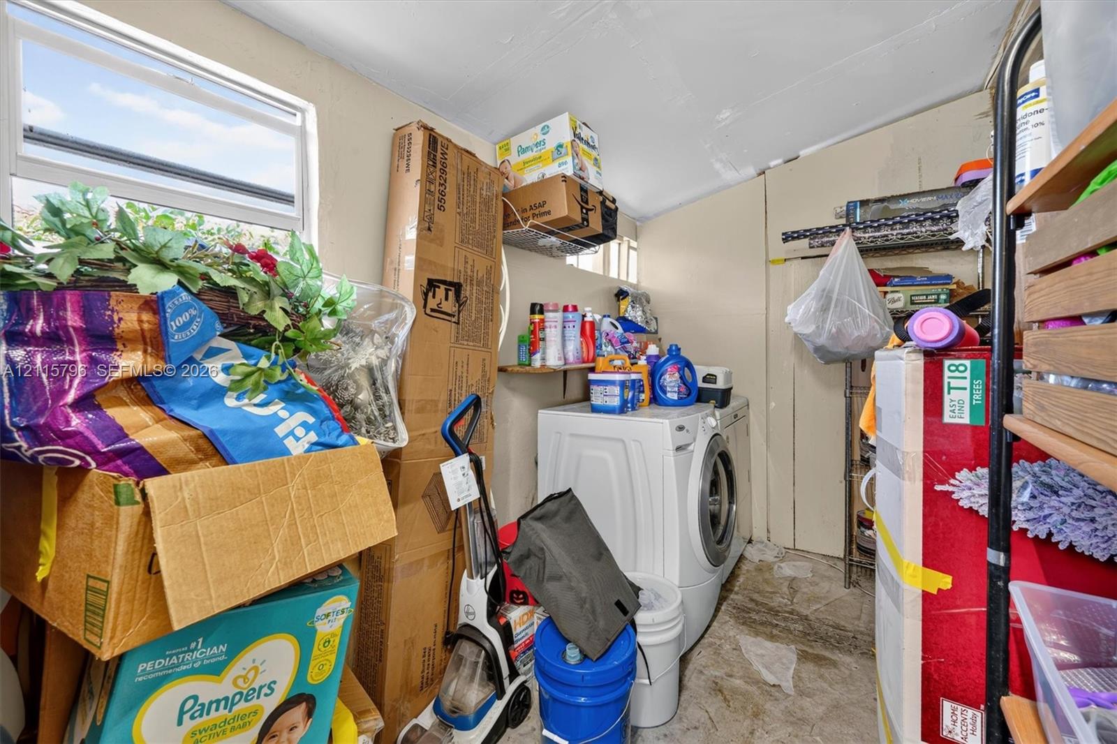 Utility area featuring a single-hung window, white wall finish, and a wall-mounted shelving unit