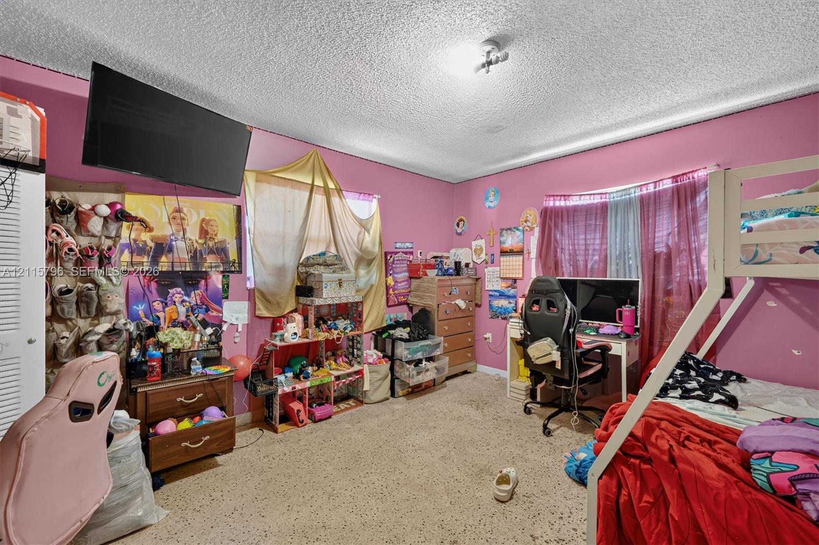 Bedroom featuring a dual-panel closet door, multi-pane window, ceiling-mounted light fixture, and textured ceiling