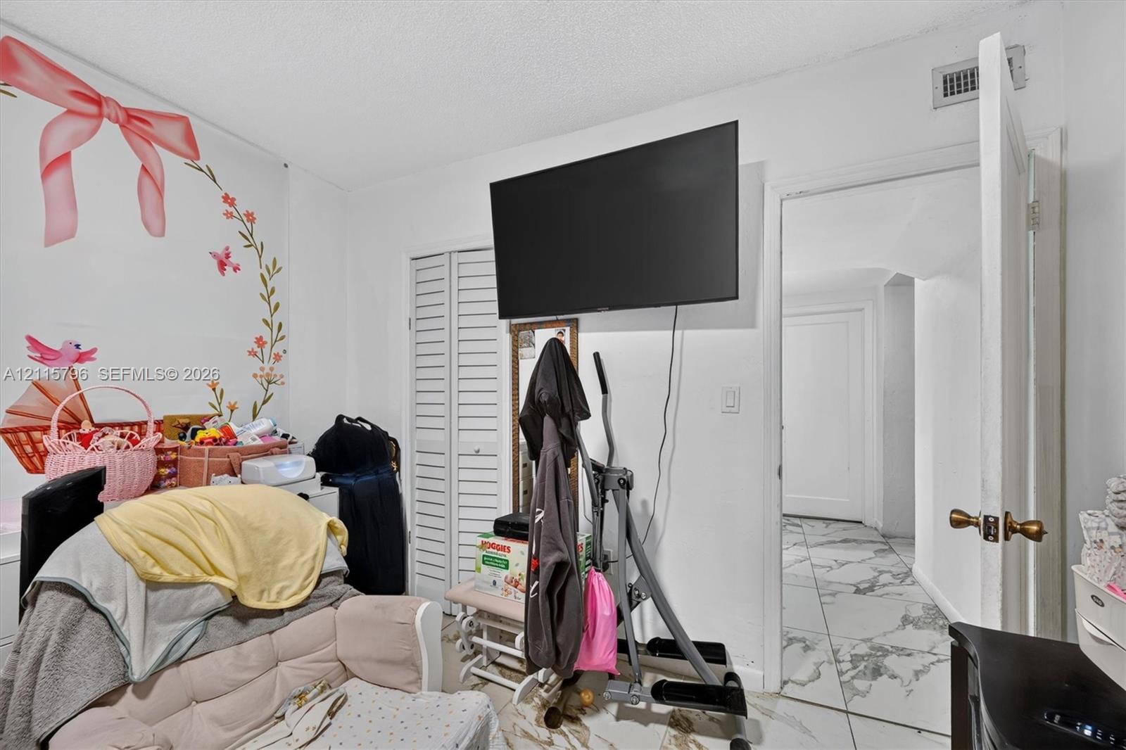 Interior space featuring white louvered closet doors, high-gloss stone-finish tile flooring, and a neutral wall palette