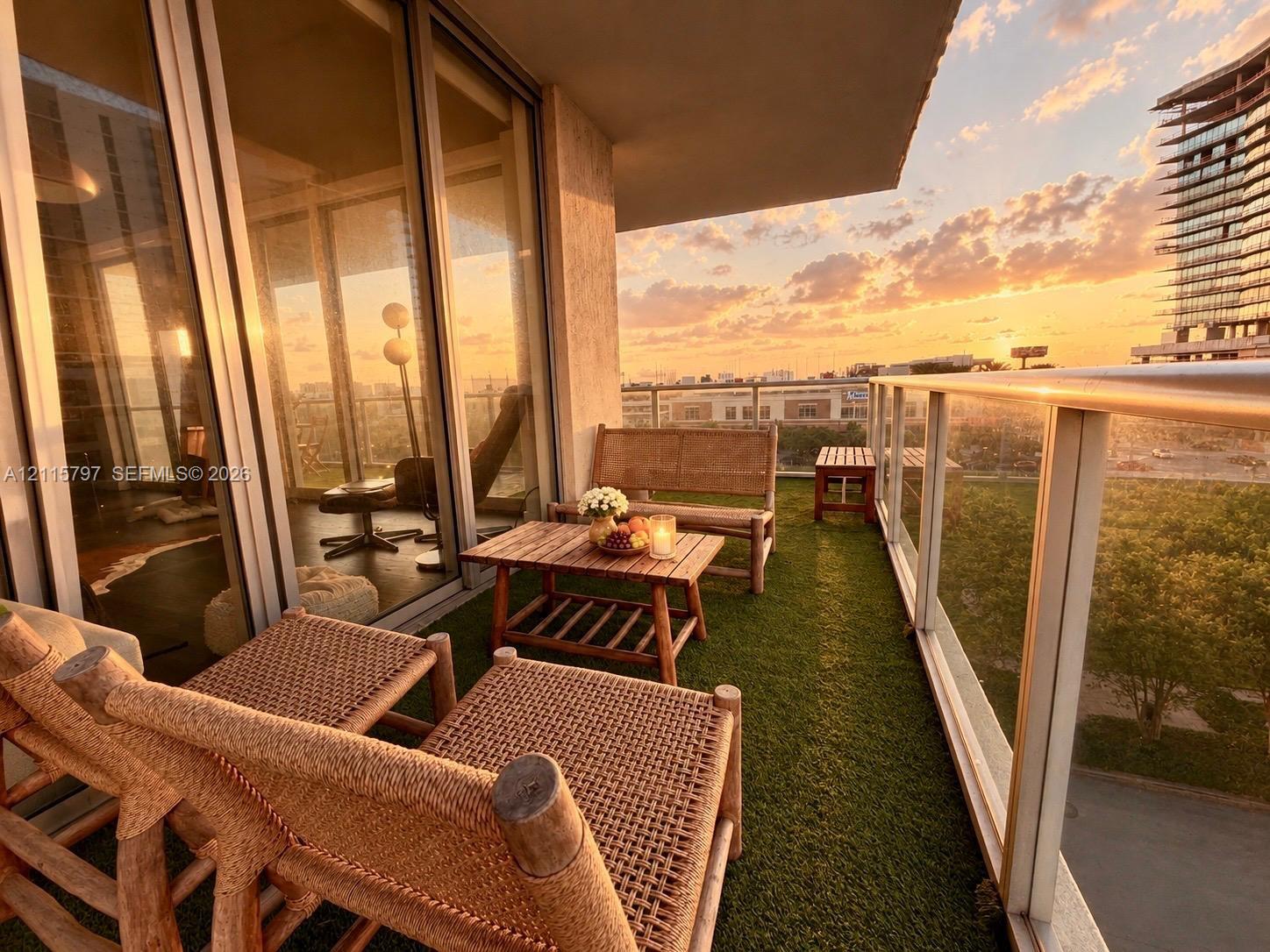 Covered private balcony featuring synthetic turf flooring, floor-to-ceiling glass sliding doors, and a metal-framed glass railing