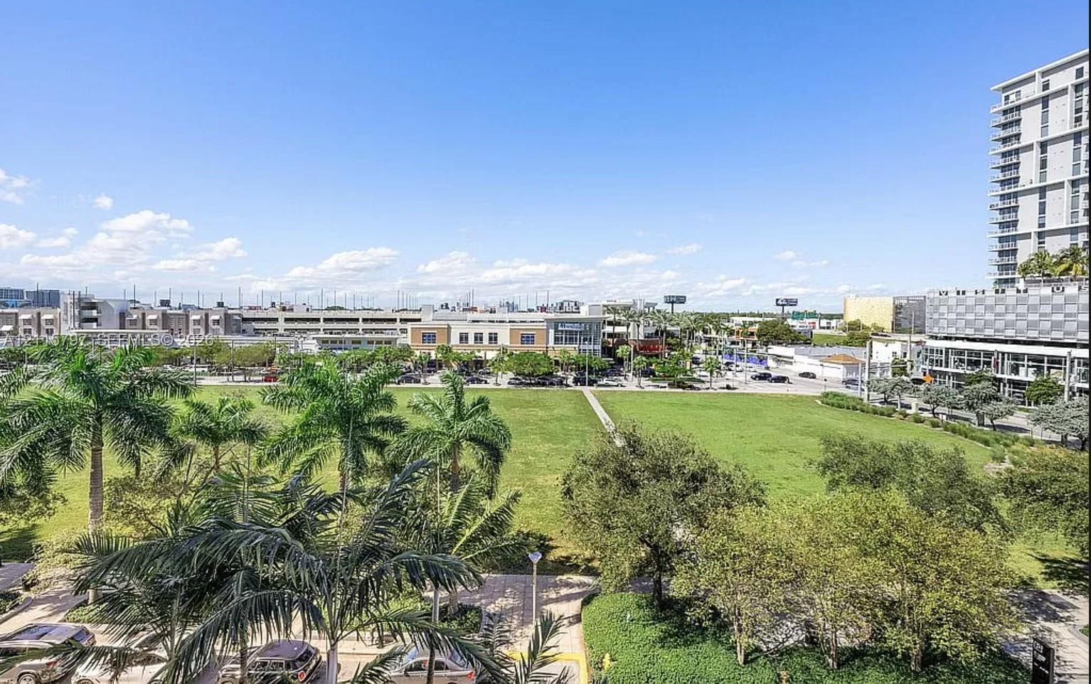 Urban landscape featuring expansive green space, mature palm trees, and multi-story architectural structures