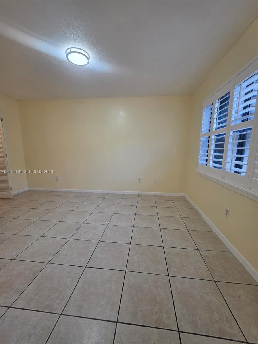 Neutral-toned ceramic tile flooring, plantation shutters, and flush-mount overhead lighting
