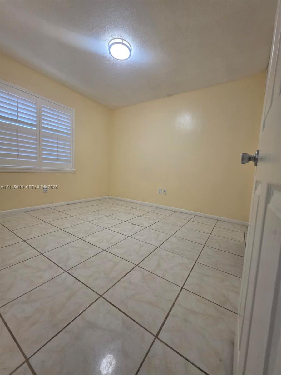 Room featuring tile flooring, plantation shutters, and a ceiling-mounted light fixture