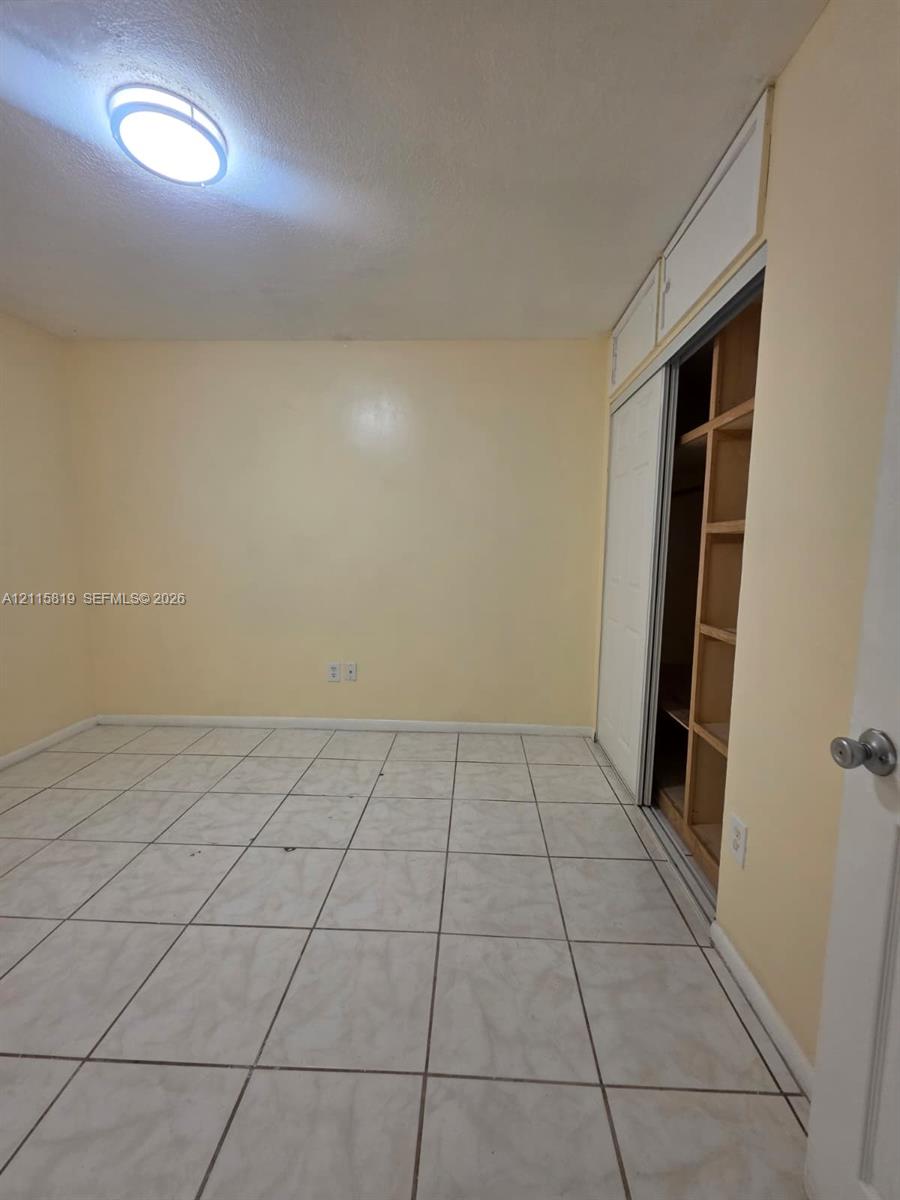 Ceramic tile flooring, flush-mount ceiling light fixture, and closet with sliding doors and integrated shelving