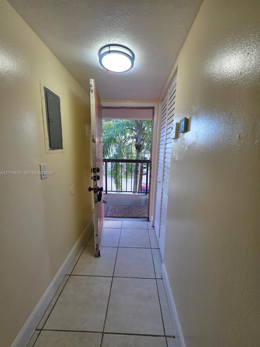 Entryway featuring large-format tile flooring, a flush-mount circular ceiling light fixture, and floor-to-ceiling louvered closet doors