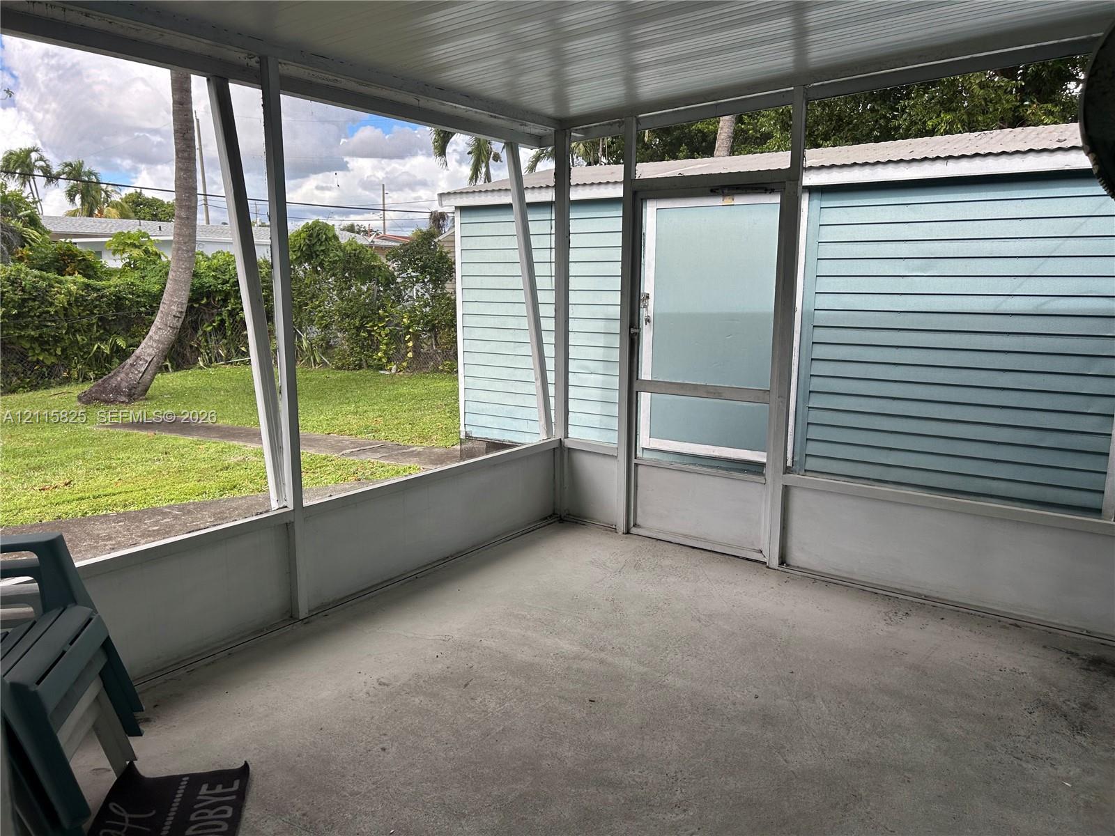 Screened-in enclosure featuring a concrete floor, metal framing, and a dedicated screen door