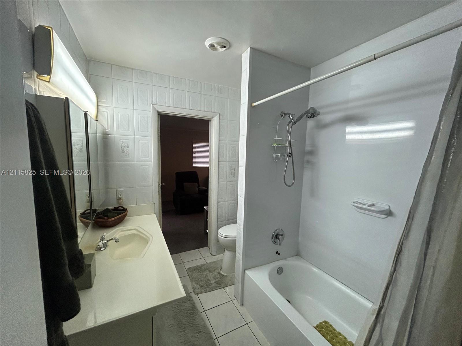 Bathroom featuring a white vanity with an integrated sink, polished chrome faucet, tiled wall surround, and a tub-shower combination with a wall-mounted shower head