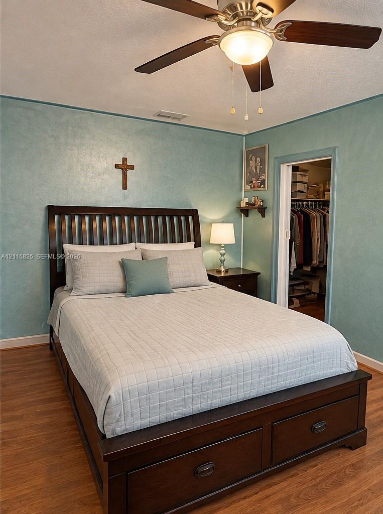 Room featuring wood-finish flooring, textured wall finish, and a ceiling fan with integrated lighting
