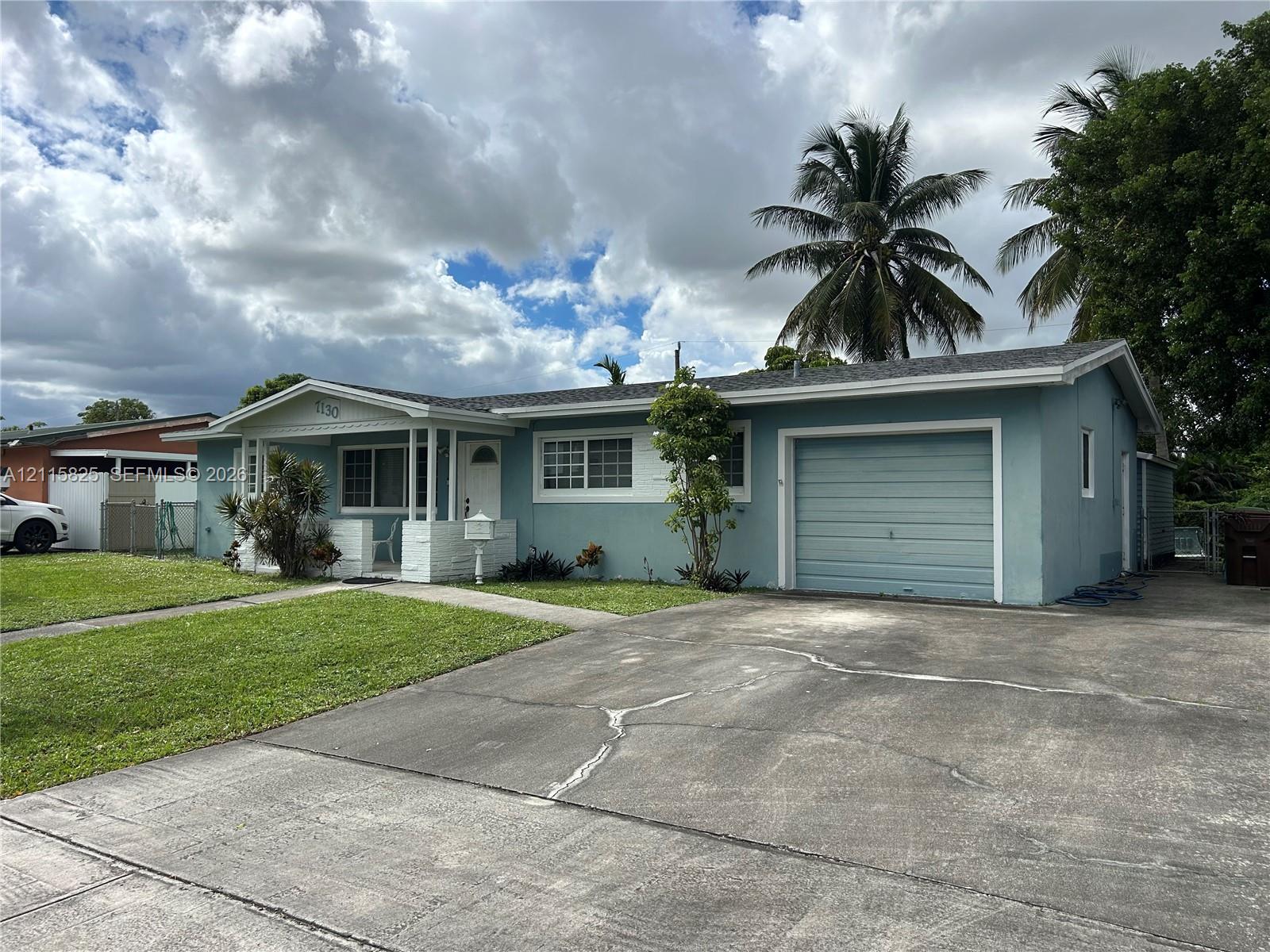 Single-story exterior featuring a covered front porch, attached garage, concrete driveway, and front lawn