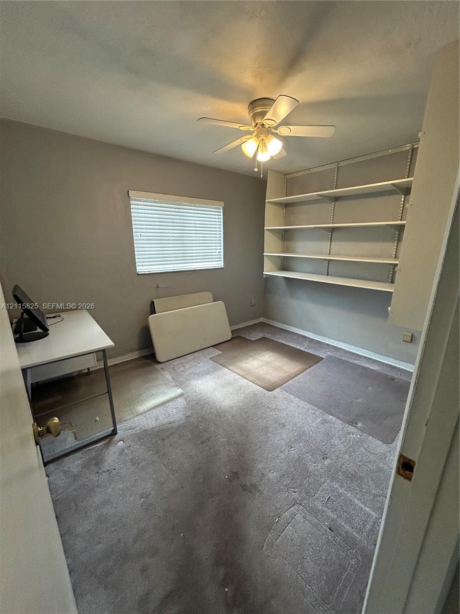 Room featuring wall-mounted shelving and a ceiling-mounted light fixture with fan